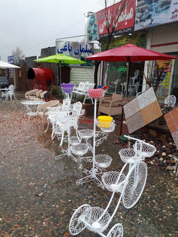 محوطه بیرونی فروشگاه مبلمان باغی در یک روز بارانی زیبا با نمایی از دوچرخه فلزی فلاور باکس ست مبلمان آلومینیوم