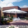 سایه بان باغی مدل پایه کنار در یک ویلای شیک به همراه ست میزوصندلی باغی کالسکه ای سفید