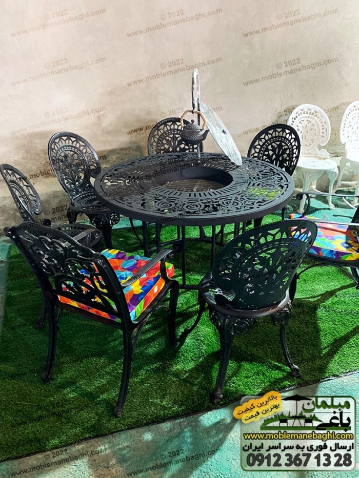 میز آتشدان گازی با پایه های بلند و استاندارد در ست ناهارخوری مبلمان باغی آلومینیومی طاووسی همگی به رنگ مشکی بر روی چمن مصنوعی در مرکز پخش میز آتشدان فروشگاه مبلمان باغی