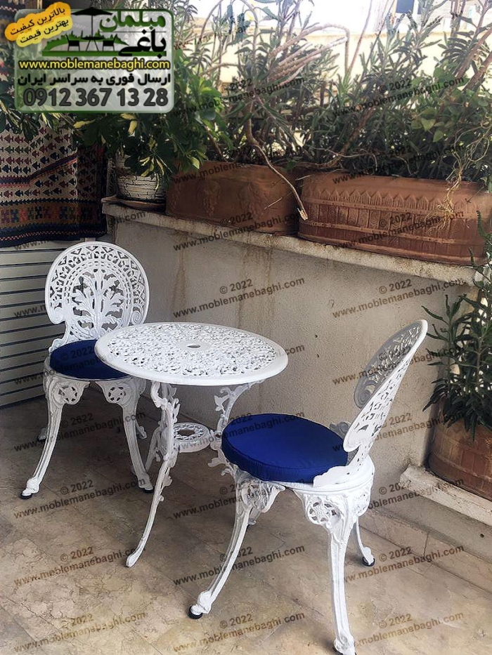 ست دو نفره میز و صندلی آلومینیومی طاووسی مدل 2022 واقع در بالکن ویلایی لاکچری؛ میز و صندلی آلومینیومی به رنگ سفید به همراه تشک‌های آبی است که بسیار ست زیبایی است. ارسالی مشتری فروشگاه مبلمان باغی در شیراز