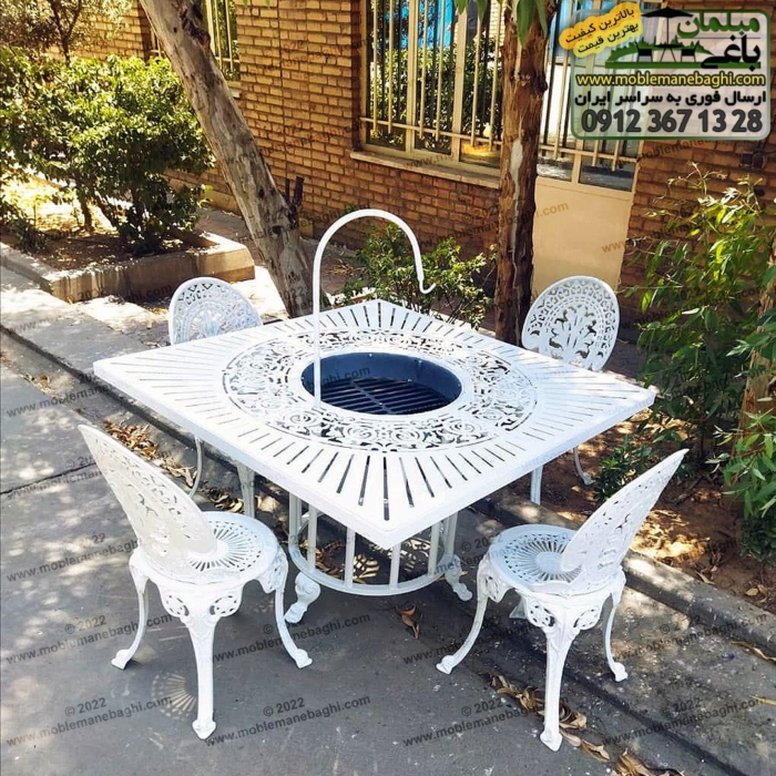 میز آتشدان منقل دار مدل مربع و صندلی محوطه طاووسی همگی به رنگ سفید در محوطه فضای باز باغی زیبا و صمیمی